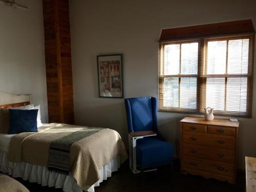 a bedroom with a bed and a chair and a window at Guadalupe Inn in Santa Fe