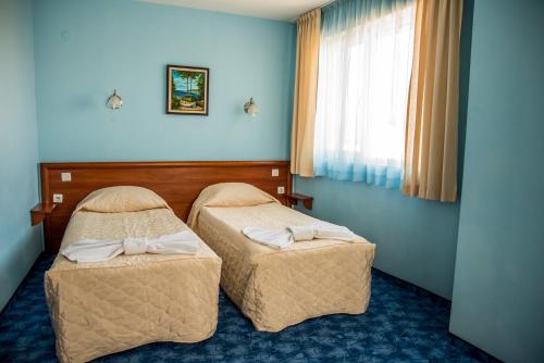 a hotel room with two beds and a window at Bariakov Family Hotel in Bansko