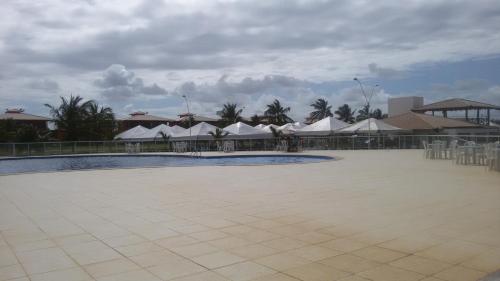 une grande cour avec des tentes blanches, des tables et des chaises dans l'établissement Apart Resort Villa das Águas, à Praia do Saco