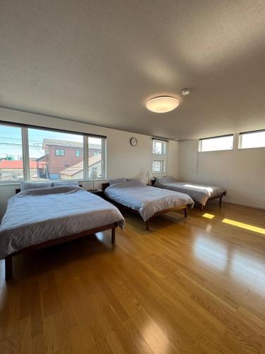 three beds in a room with wood floors and windows at 函館 FabulousHouse 一棟貸し最大17名 in Hakodate