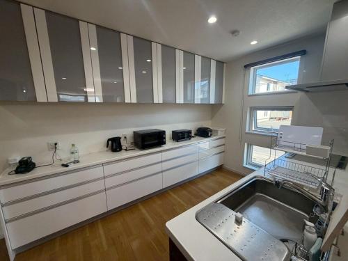 a kitchen with a sink and a large kitchen with a window at 函館 FabulousHouse 一棟貸し最大17名 in Hakodate