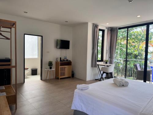 a bedroom with a white bed and a balcony at Phuket Muay Thai Hotel Rawai Beach in Rawai Beach