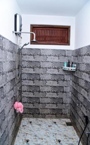 a shower in a bathroom with a brick wall at Ella River Breeze Homestay in Ella