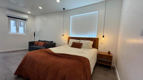a bedroom with a bed and a chair and a window at AngraHouse in Angra do Heroísmo