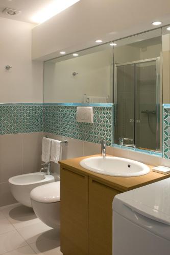 a bathroom with a sink and a toilet and a mirror at Residence Lungomare - Charming apartments in Riccione