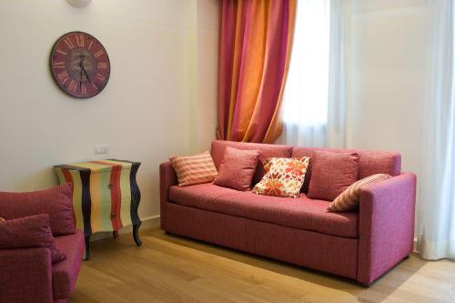 a living room with a pink couch and a clock at Residence Lungomare - Charming apartments in Riccione