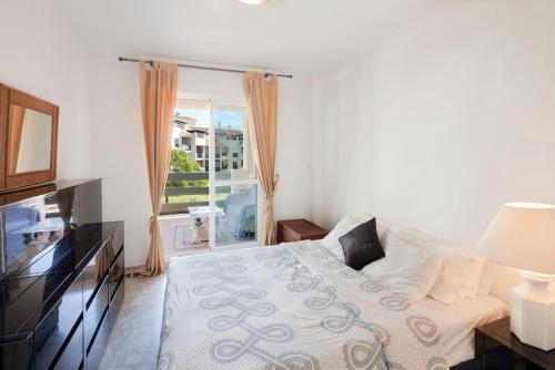 a white bedroom with a bed and a window at Lorcrimar 3 in Marbella