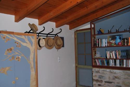 Villa Spiti Elaionas في كارفاس: غرفة مع رف للكتب وجدار مع القبعات