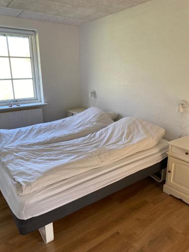 an unmade bed in a bedroom with a window at Ellemose Bed and Breakfast in Lemvig