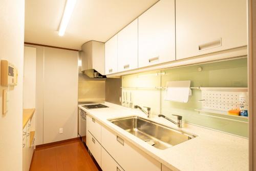 a kitchen with white cabinets and a sink at HP Jōshin in Nagoya