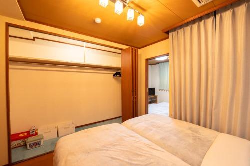 a small bedroom with a bed and a window at HP Jōshin in Nagoya