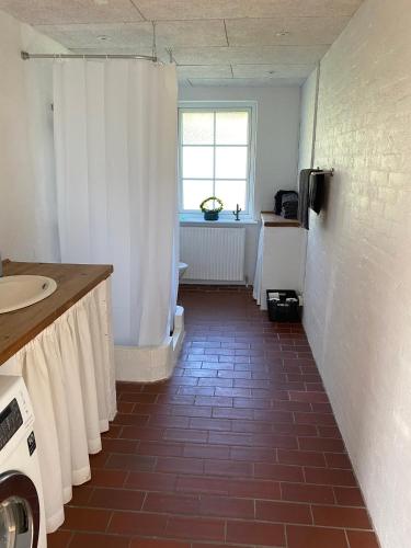 a bathroom with a tile floor and a white shower curtain at Ellemose Bed and Breakfast in Lemvig