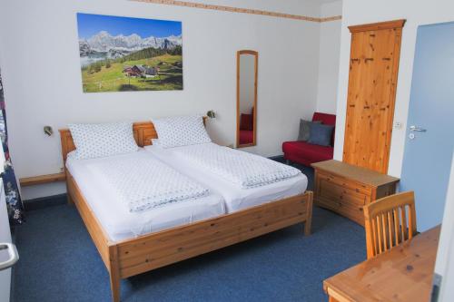 a bedroom with a wooden bed and a red chair at Hotel Stangl in Hamm