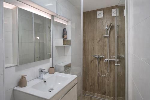 a white bathroom with a sink and a shower at DINLUX Apartment in Maribor