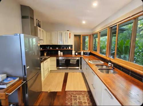 a kitchen with white cabinets and a stainless steel refrigerator at The Black Cockatoo - Secret Garden Treetops Home in Katoomba