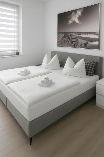 a white bedroom with a large bed with white pillows at Fewo-Exklusiv "Seeblick" in Großräschen