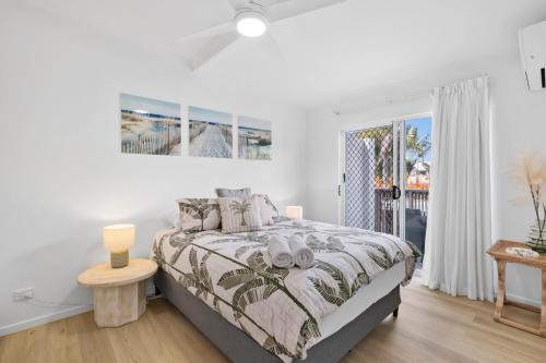 a white bedroom with a bed and a window at Beachcomber Peregian Beach in Peregian Beach
