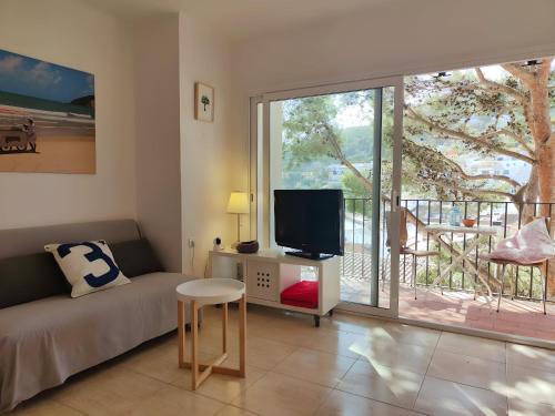 a living room with a couch and a tv and a balcony at Stunning Intimate views. Terrace Rooftop. Wifi in Tamariu