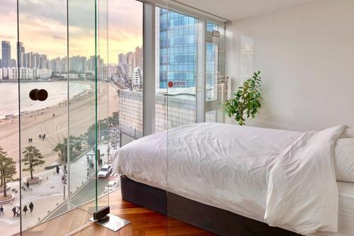 a bedroom with a white bed and a large window at Busan Neouigyejeol in Busan