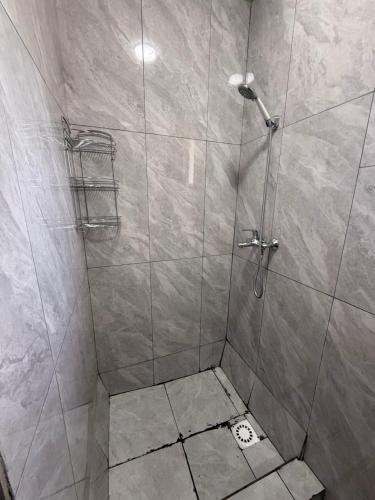 a shower stall with a glass door with a shower at Guesthouse Chon - Kemin in Shabdan