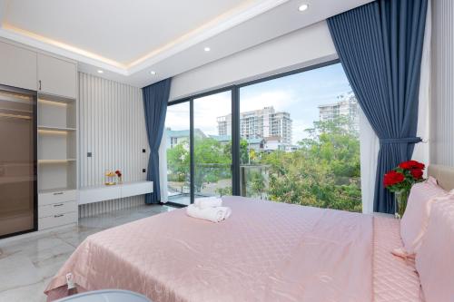 a bedroom with a pink bed and a large window at Villa B2-34 Long Cung in Vung Tau