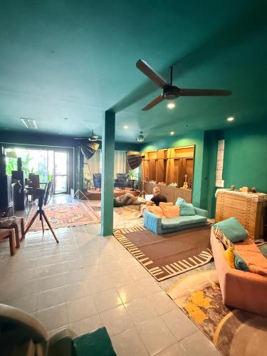 a living room with green walls and a ceiling fan at Hostel Cafe13 in Ko Phangan