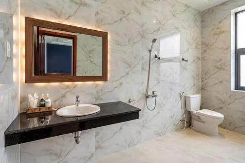 a bathroom with a sink and a toilet and a mirror at Villa B2-10 Long Cung in Vung Tau