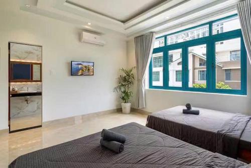 a bedroom with two beds and a large window at Villa B2-10 Long Cung in Vung Tau