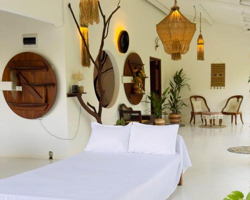 a bedroom with a white bed with a tree on the wall at Ceylon Marley Villa in Talawa
