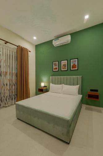 a bedroom with a large bed with a green wall at Mulberry Living in Negombo