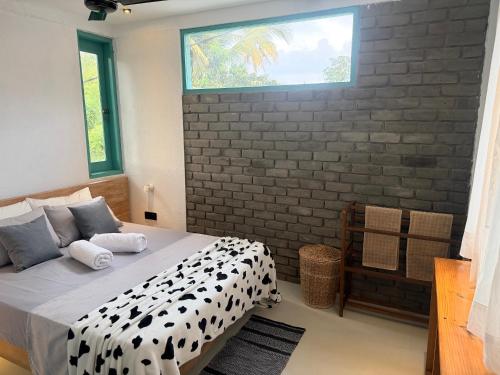 a bedroom with a black and white bed and a brick wall at casa luna villa in Narigama