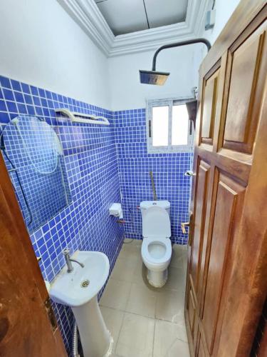 a blue tiled bathroom with a toilet and a sink at FOKOU House in Yaoundé