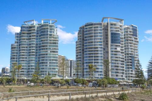 two tall buildings next to a beach with palm trees at Reflections Tower Two in Gold Coast