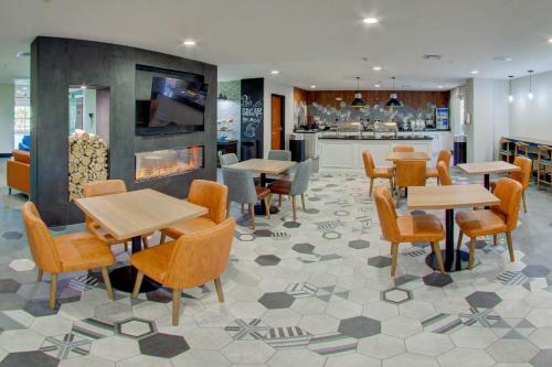 a restaurant with tables and chairs and a fireplace at Comfort Suites Newport News Airport in Newport News