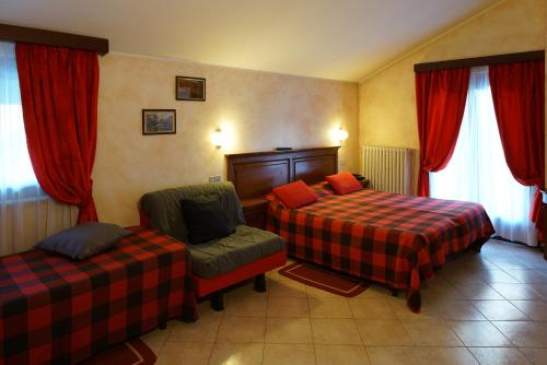 a hotel room with two beds and a chair at Hotel Al Caminetto in Valtournenche