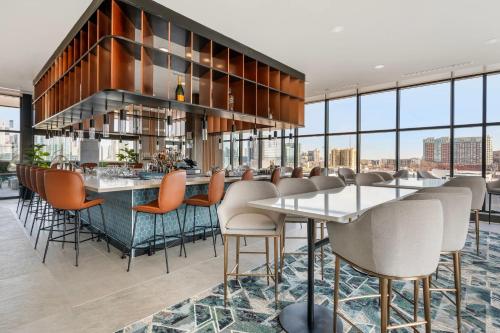 a bar with chairs and tables in a room with windows at Cambria Hotel Nashville Midtown in Nashville