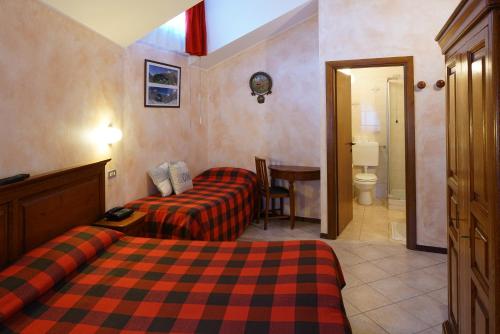 a hotel room with two beds and a bathroom at Hotel Al Caminetto in Valtournenche