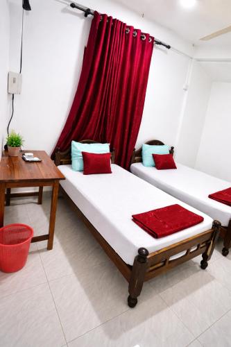 two beds in a room with a red curtain at Pearl Rest in Mannar