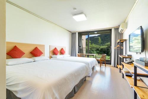 a bedroom with two beds and a large window at Dammora Resort in Seogwipo