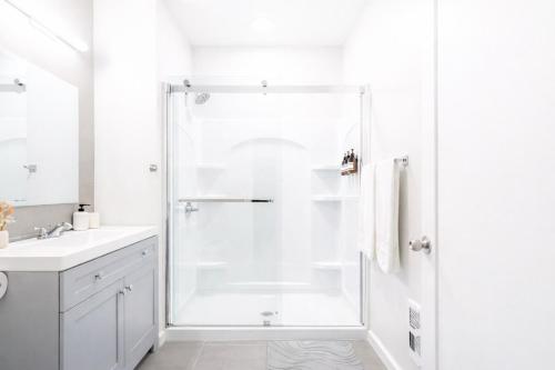 a white bathroom with a shower and a sink at DTWN Yale Wooster Square Laundry in New Haven