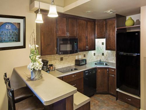 a kitchen with wooden cabinets and a black refrigerator at London Bridge Resort in Lake Havasu City