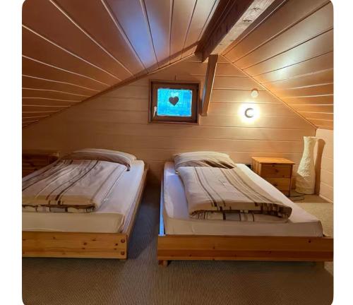 two beds in a room with a attic at Gîte le Nid in Langatte