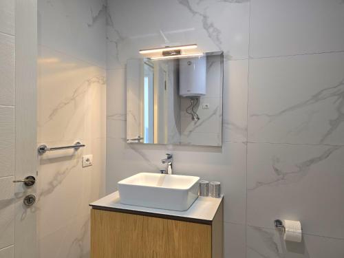 a white bathroom with a sink and a mirror at White Moon Apartment 301 in Lalzit Bay