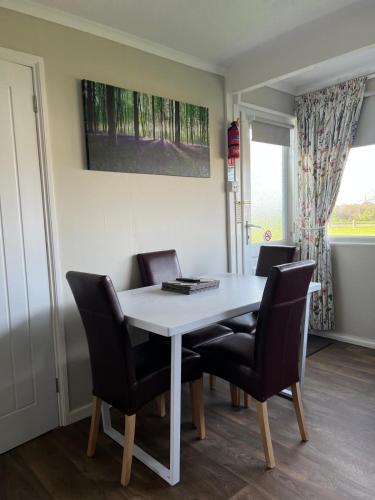 a dining room table with chairs and a white table at Dragon Chalet 1 , 155 Sunbeach Holiday Village, Scratby in Scratby