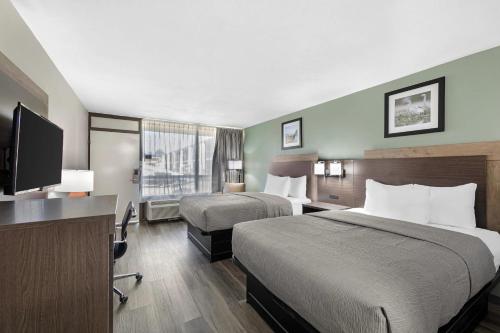 a hotel room with two beds and a flat screen tv at Quality Inn Columbus, MS in Columbus
