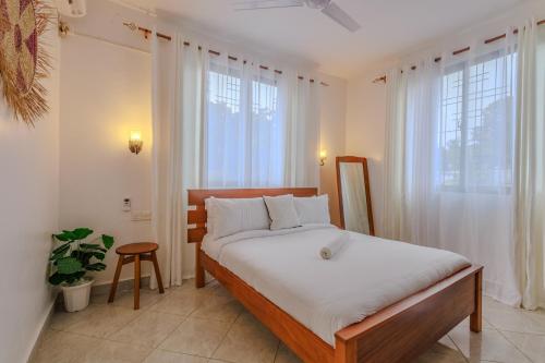 a bedroom with a bed with white sheets and a window at Marahaba Holiday Suites Ground Floor 1BR 5 Min Drive to Nomad Beach in Ukunda