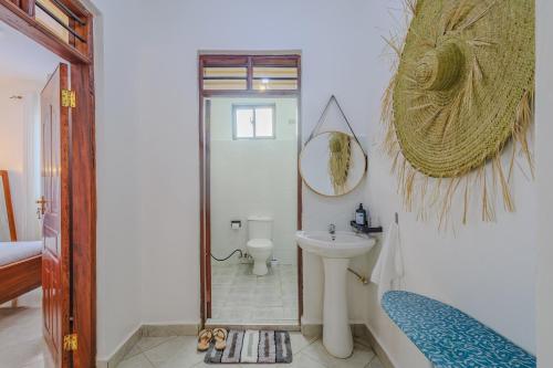 a bathroom with a sink and a toilet and a mirror at Marahaba Holiday Suites Ground Floor 1BR 5 Min Drive to Nomad Beach in Ukunda