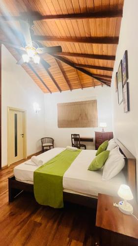 a bedroom with a large bed with a green blanket at Mara Villa Katunayake - 5 Mins to Colombo Airport in Katunayaka