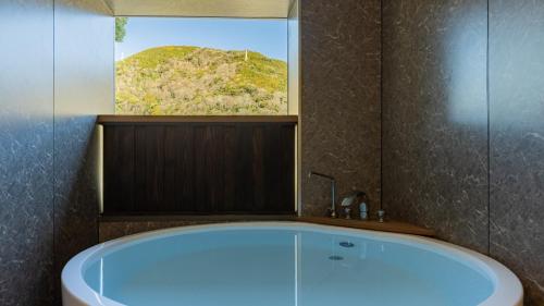 eine Badewanne in einem Badezimmer mit Fenster in der Unterkunft HOTEL nehako in Hakone
