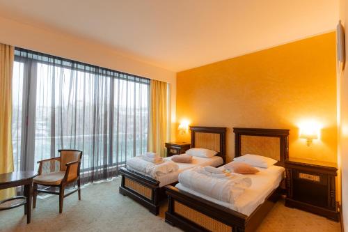 a hotel room with two beds and a table and chairs at Hotel Zodiac by Sofra in Constanţa